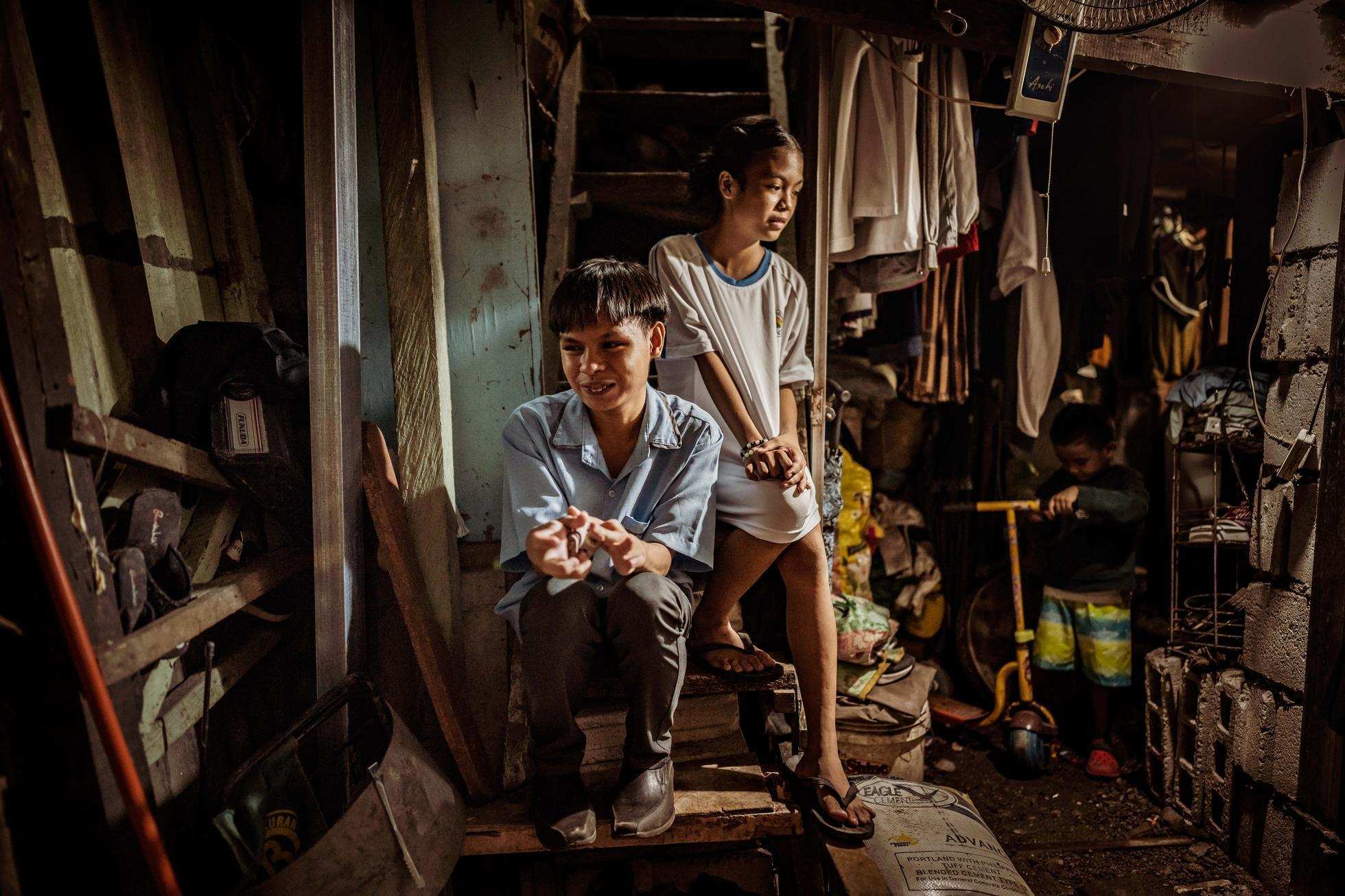 Ein Junge und ein Mädchen sitzen auf den Treppenstufen ihrer vollgestellten, engen Wohnung in einem Slum in Manila. (Quelle: Jakob Studnar) Kinder in ihrer vollgestellten Behausung in Manilas Slums (Foto: Jakob Studnar)