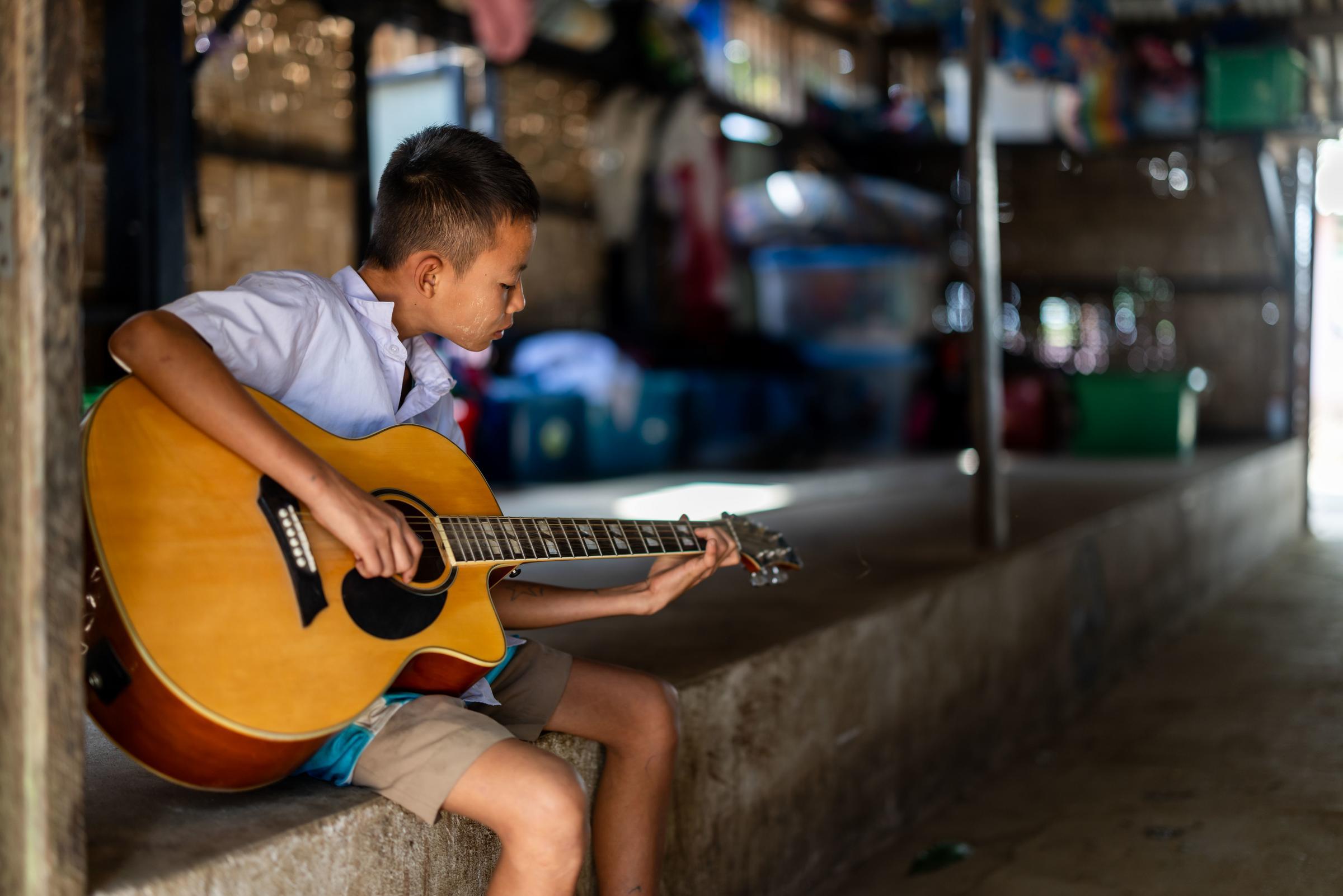 Kind in thailändischem Projekt spielt Gitarre. (Foto: Kindernothilfe / Lars Heidrich)