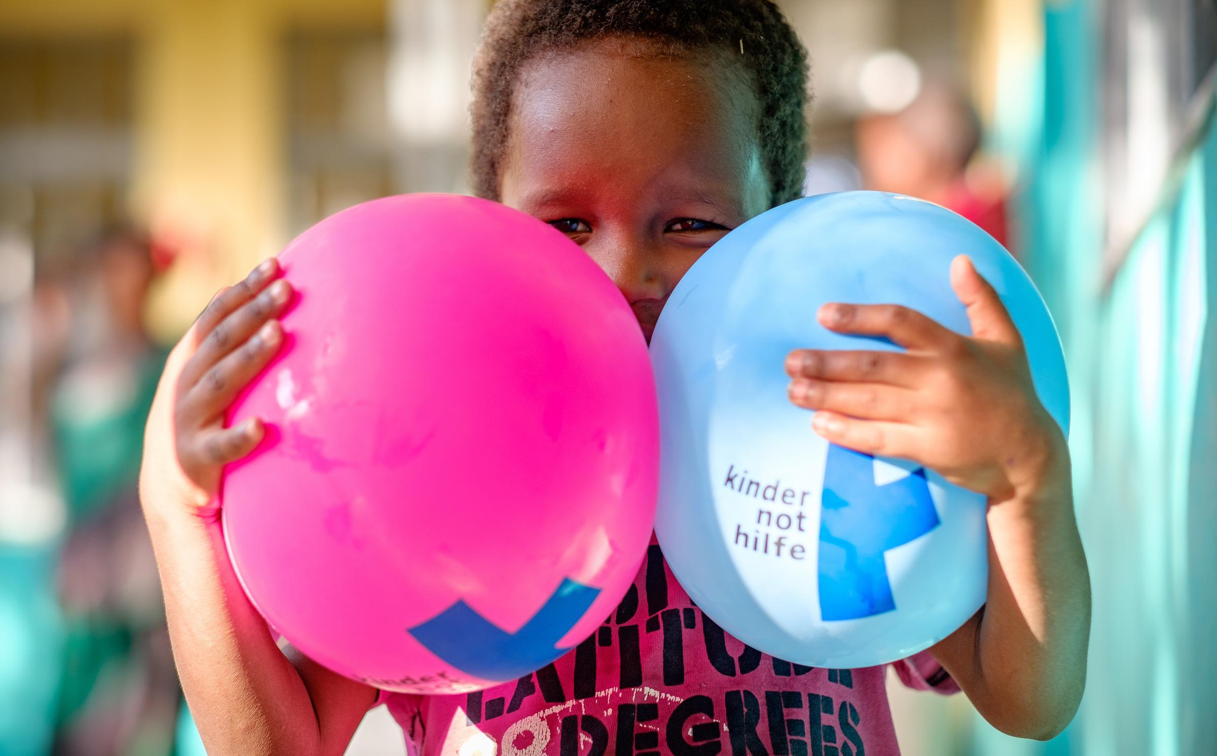 Ein kleines Mädchen hält sich zwei Luftballons vors Gesicht. (Foto: Jakob Studnar)