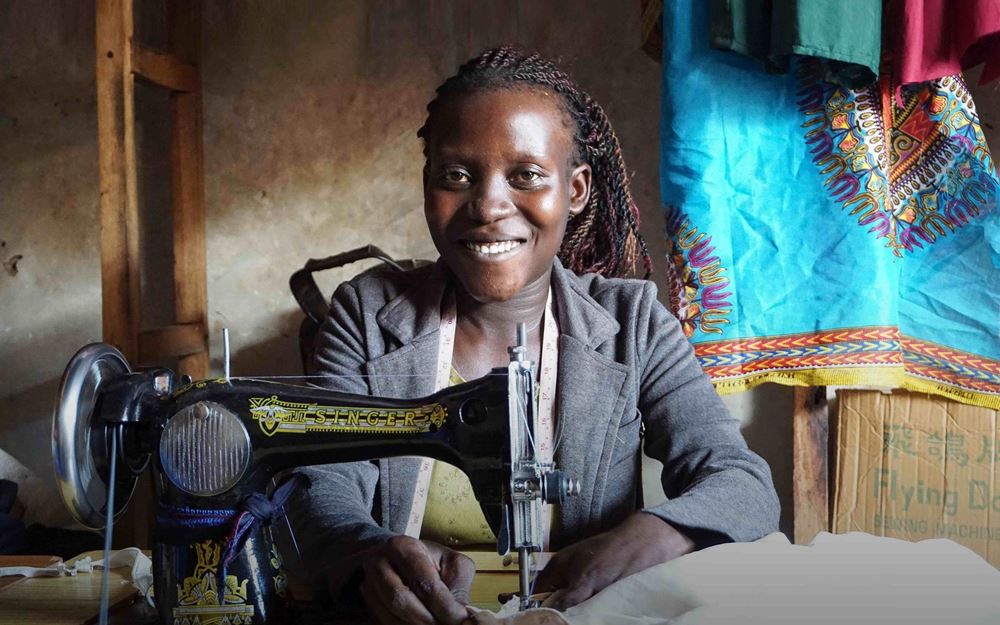 Reportage Uganda: Aufschwung am Äquator; Foto: Frau sitzt an der Nähmaschine (Quelle: Ludwig Grunewald / Kindernothilfe) Reportage Uganda: Aufschwung am Äquator; Foto: Frau sitzt an der Nähmaschine (Quelle: Ludwig Grunewald / Kindernothilfe)
