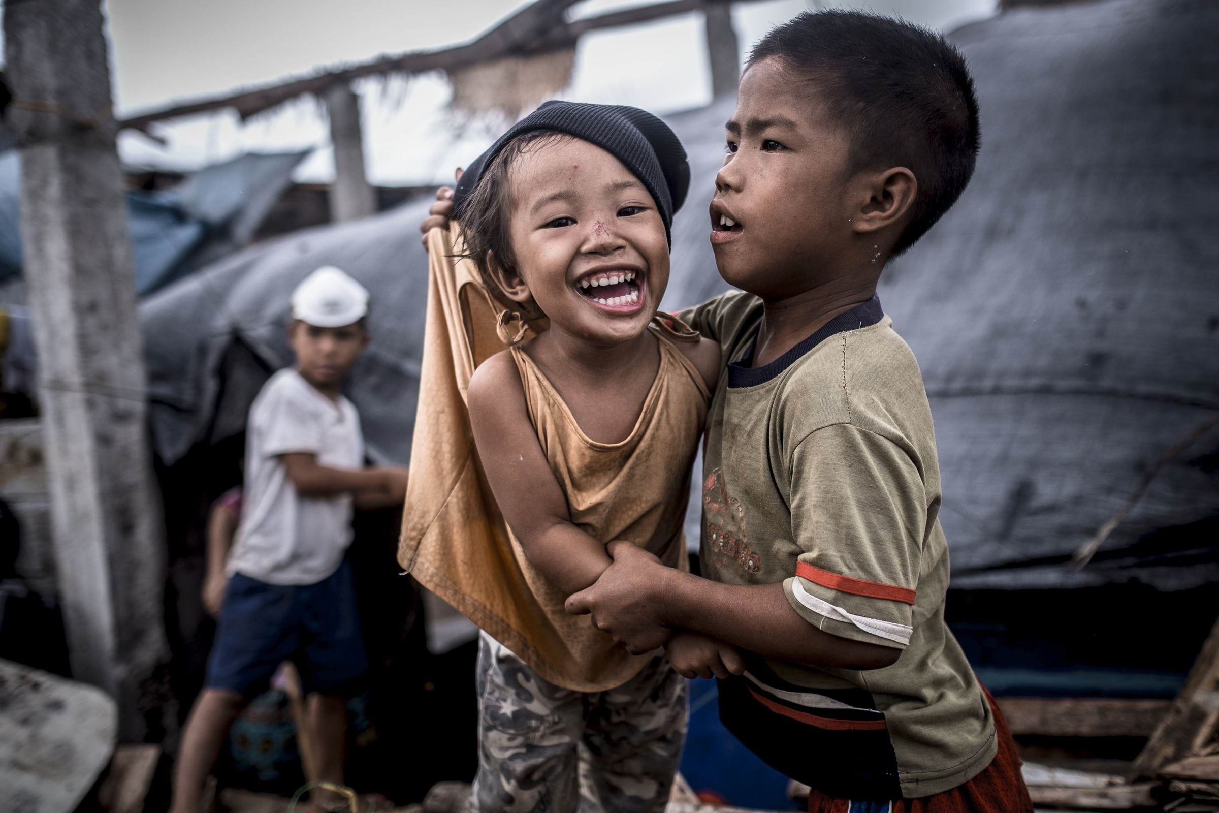 Zwei Jungen halten sich lachend im Arm. Um sie herum herrscht Chaos nach dem Taifun Haiyan auf den Philippinen. (Quelle: Jakob Studnar) Zwei Jungen halten sich lachend im Arm. Um sie herum herrscht Chaos nach dem Taifun Haiyan auf den Philippinen. (Quelle: Jakob Studnar)